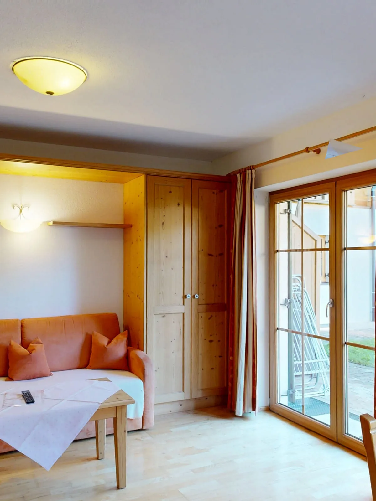 Wohnzimmer mit orangefarbenem Sofa und Glastür zum Balkon.