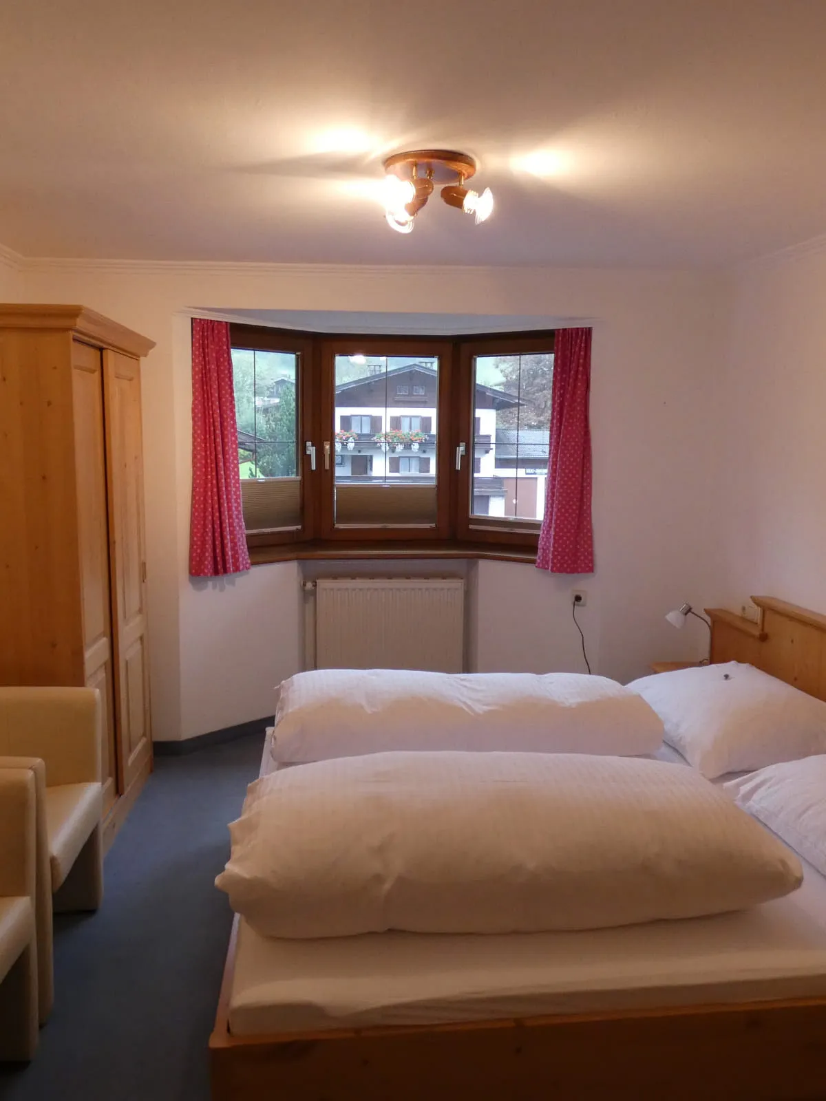 Helles Schlafzimmer mit Bett und zwei Stühlen, Fenster zu sehen.