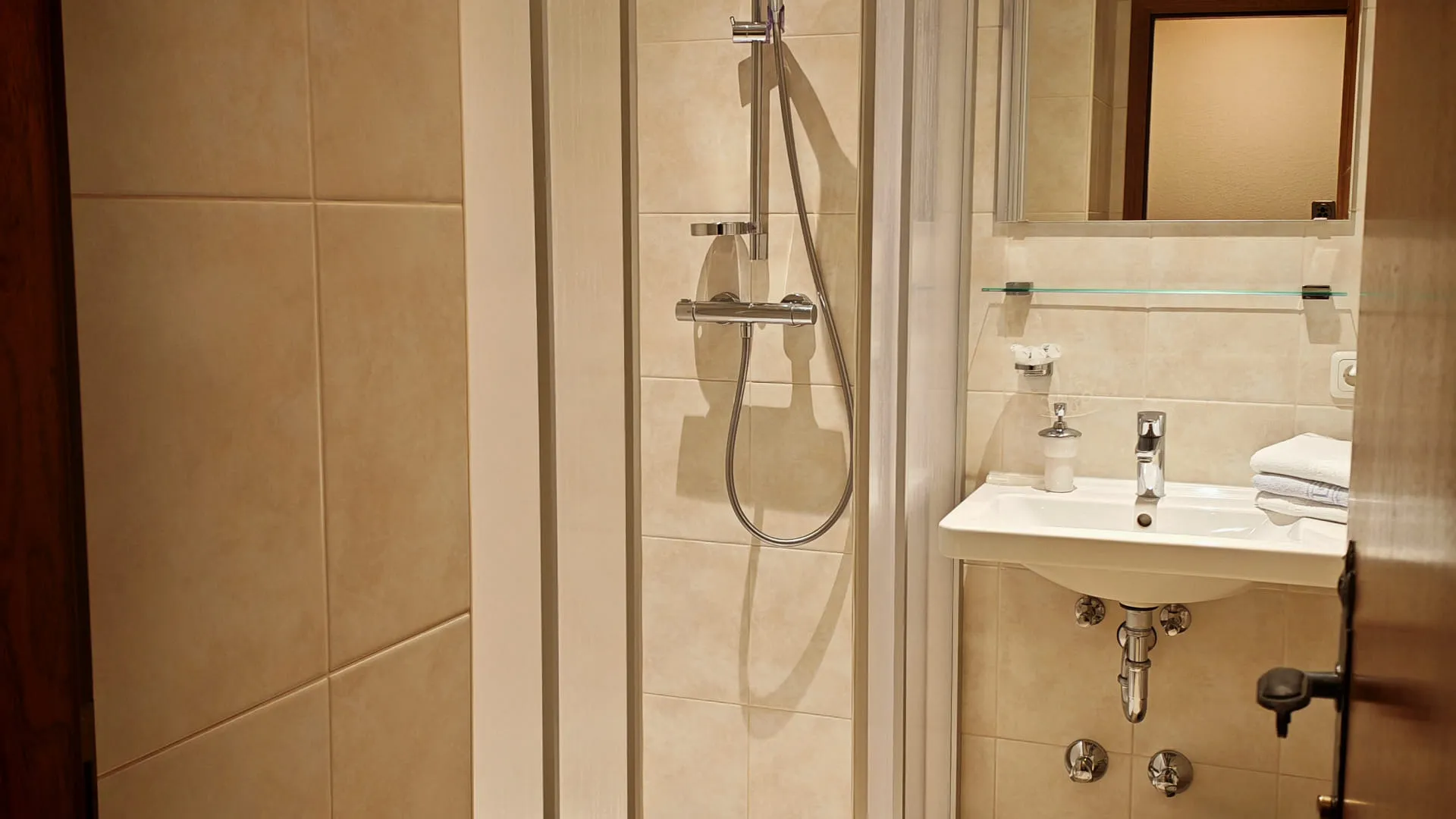 Badezimmer mit Dusche, Waschbecken und Spiegel