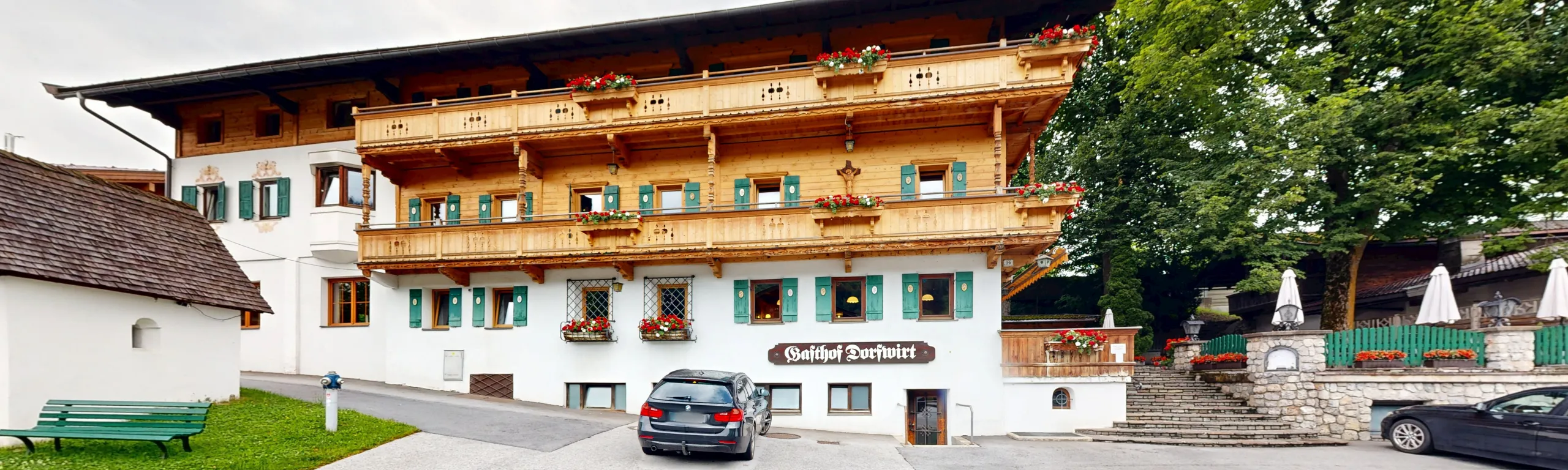 Alpenhaus mit Balkon und grüner Umgebung, Parkplatz und Restaurant