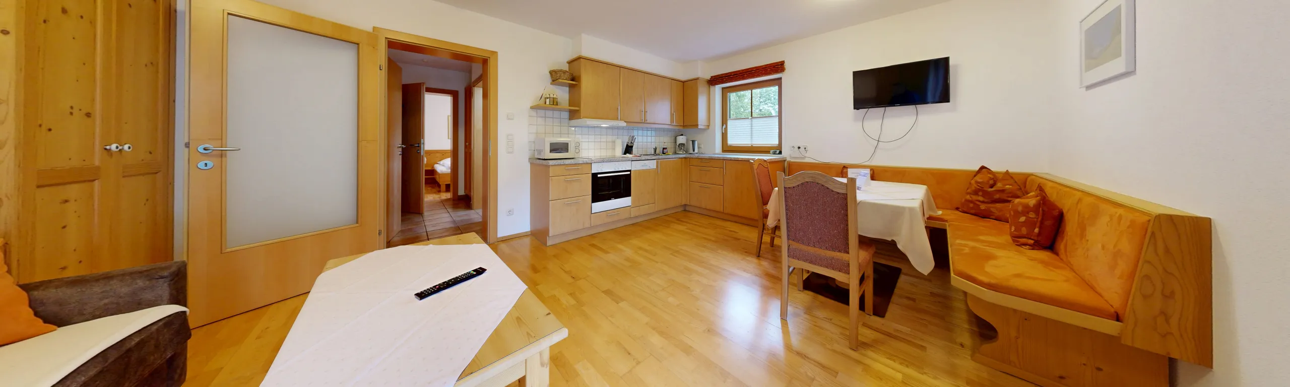 Helle Wohnung mit Holzinterieur, Küche, Essbereich und gemütlicher Sitzecke.