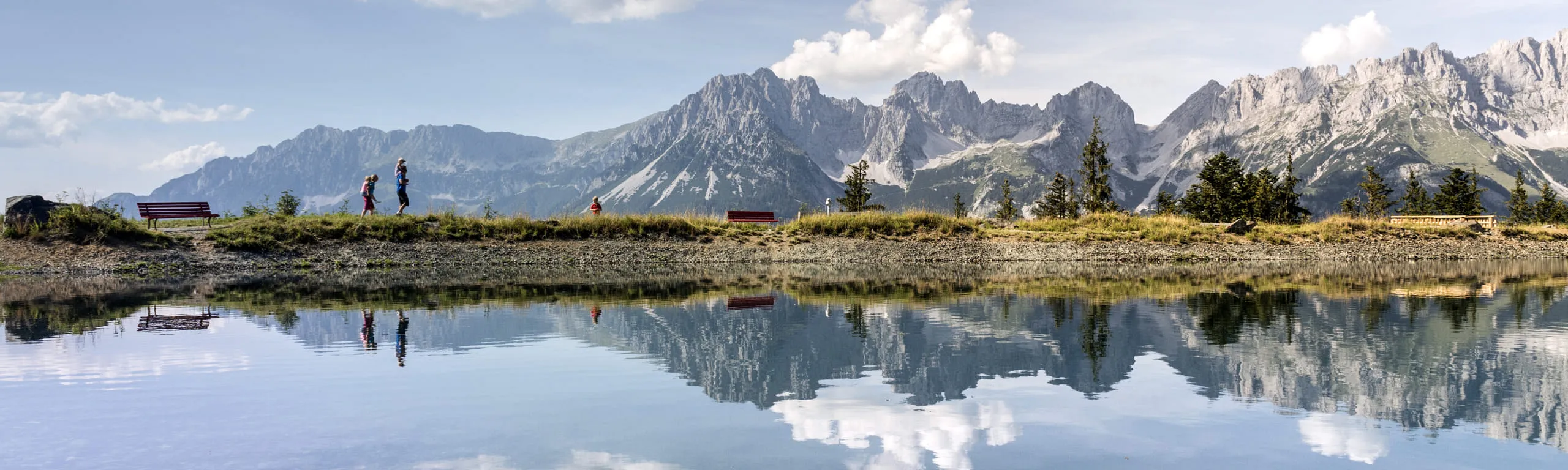 Panoramablick auf den Astbergsee mit Bergen und reflektierenden Wasseroberfläche.