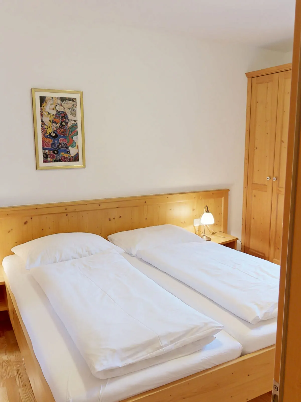 Schlafzimmer mit zwei Betten, Nachttischen und einem Gemälde an der Wand