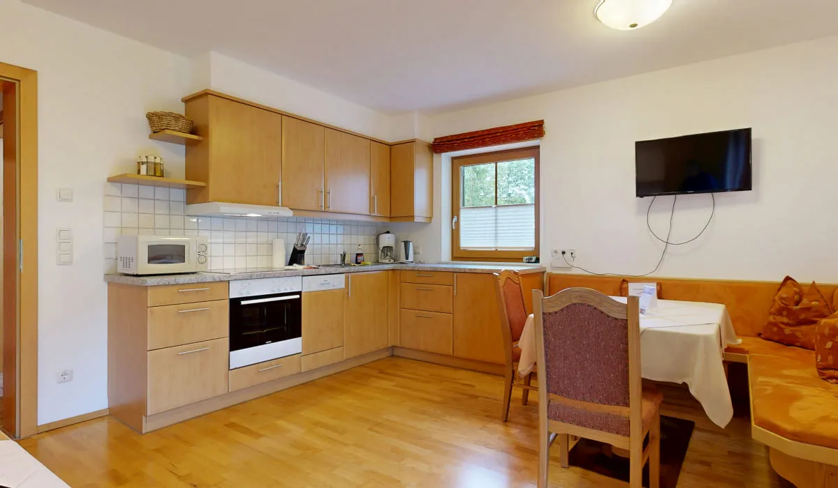 moderne Küche mit Holzschränken, Tisch und Fernseher