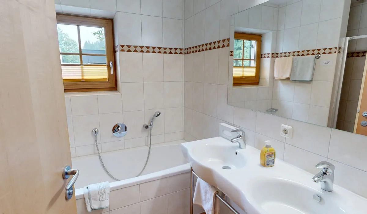 Badezimmer mit Badewanne, Waschbecken und Fenster