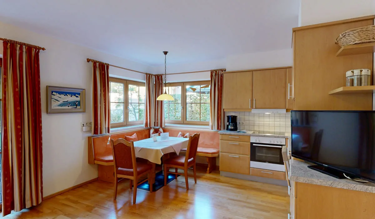 Küche mit Esstisch, Stühlen, Fernseher und Fenstern
