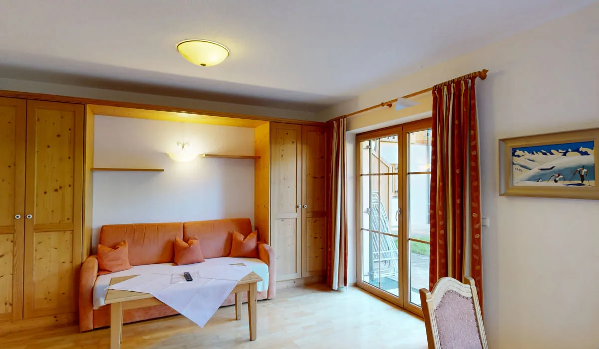 Wohnzimmer mit Sofa, Tisch und Tür zur Außenterrasse