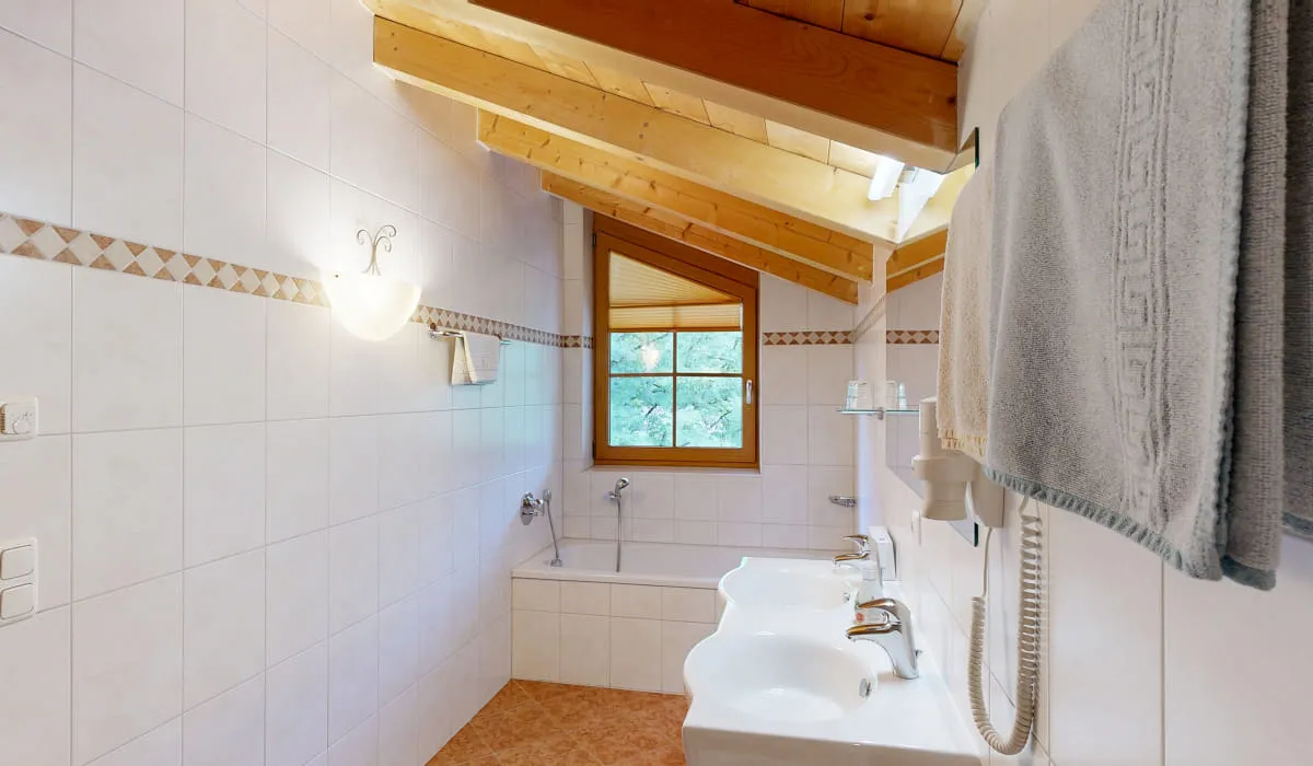 Helles Badezimmer mit Holzdecke, zwei Waschbecken und Fenster