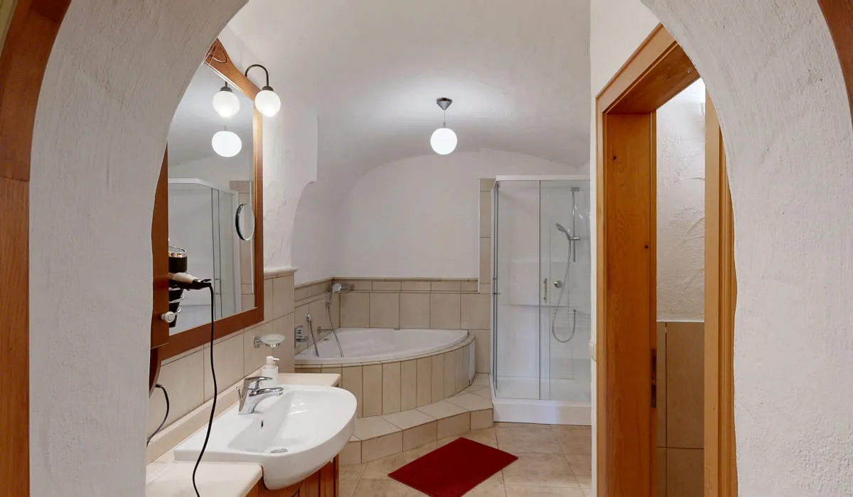 Badezimmer mit Dusche, Badewanne, Waschbecken und Spiegel