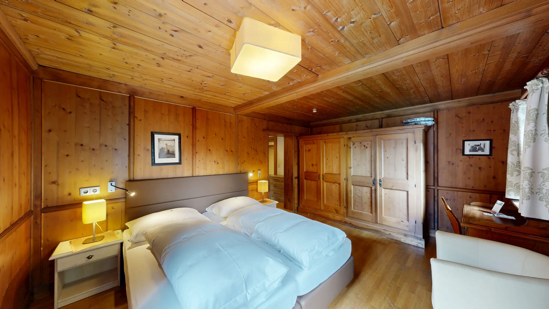 Holzverkleidetes Zimmer mit zwei Betten, Nachttisch und Kleiderschrank.