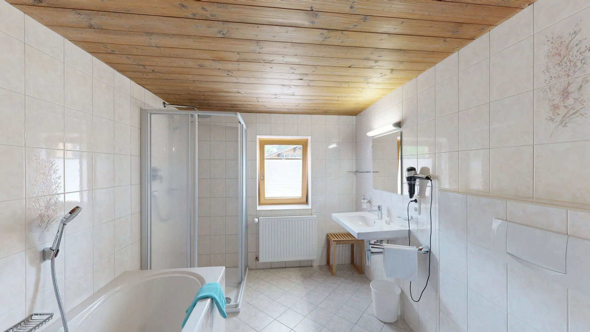 Badezimmer mit Dusche, Badewanne, zwei Waschbecken und Holzdecke.