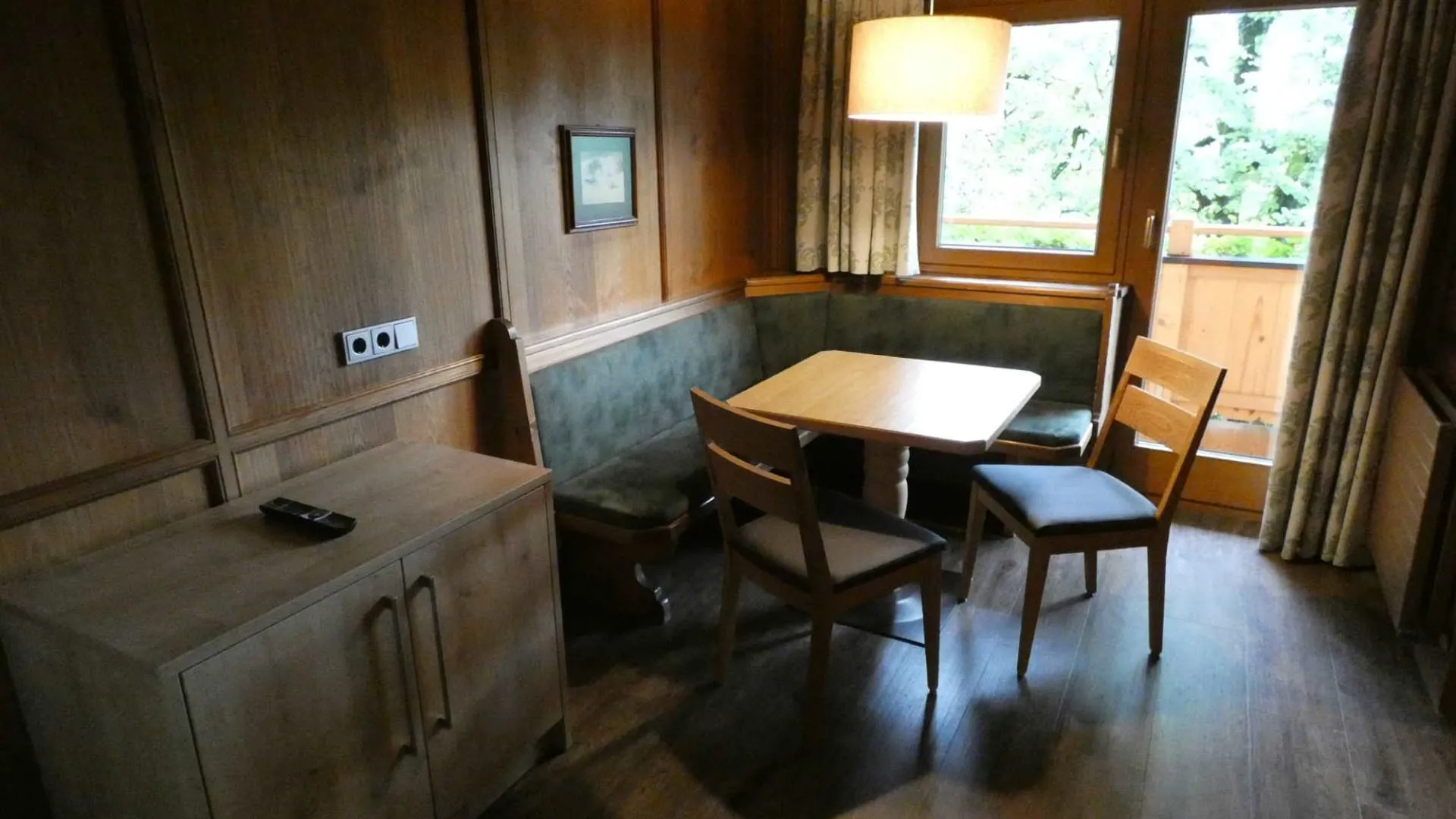 Heller Wohnraum mit Tisch und Stühlen, Holzmöbeln und Fenster mit Blick nach außen.