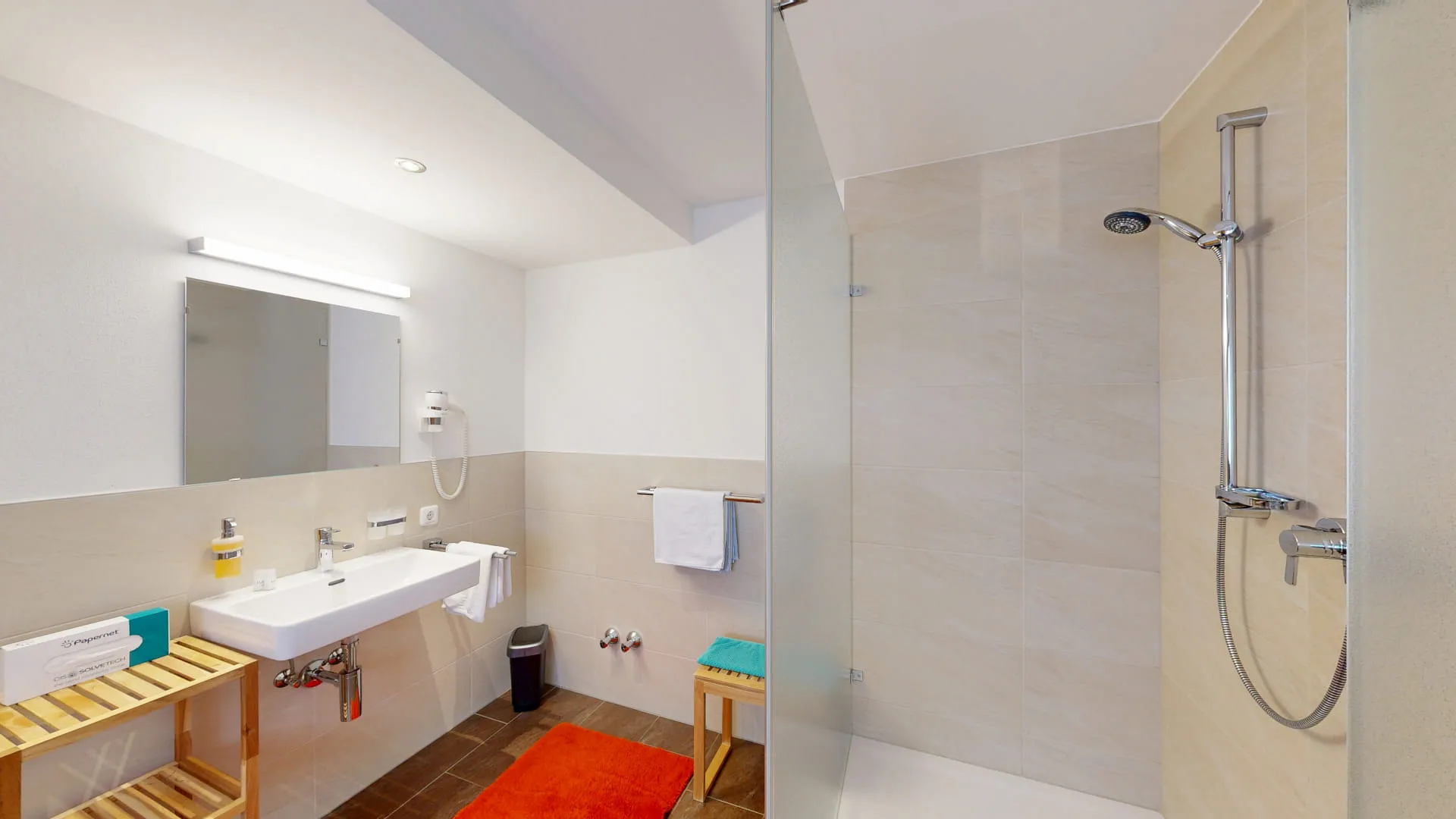 Helles Badezimmer mit Waschbecken, Spiegel und Duschbereich